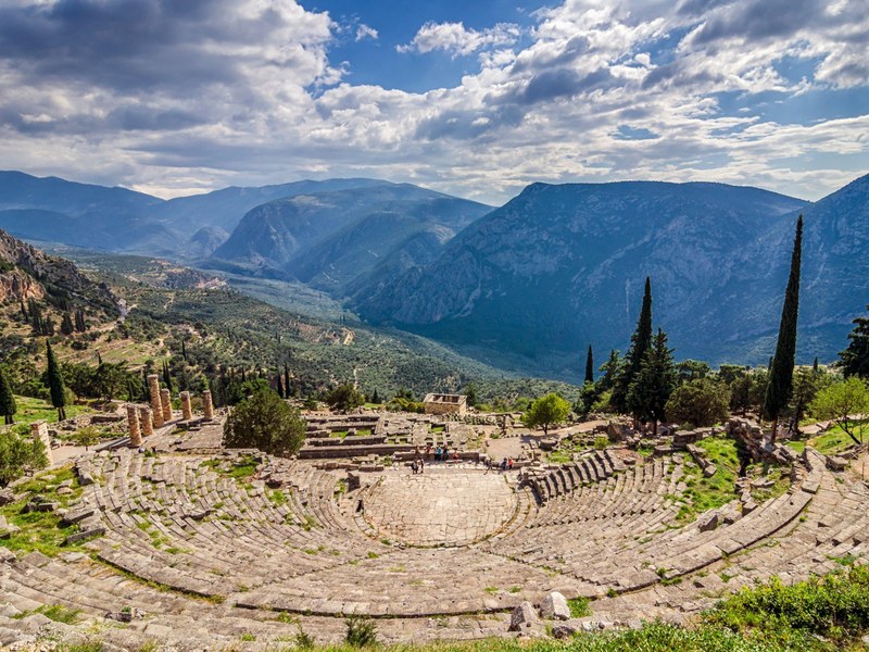 The ancient theatre and sanctuary of Delphi overlooking a green valley of olive groves