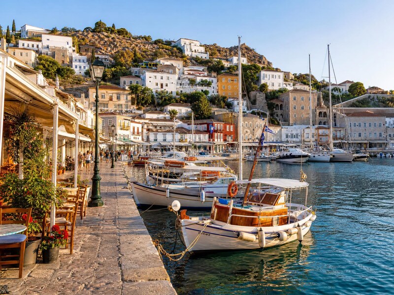 Traditional boats moored in a Greek island harbour lined with stone houses
